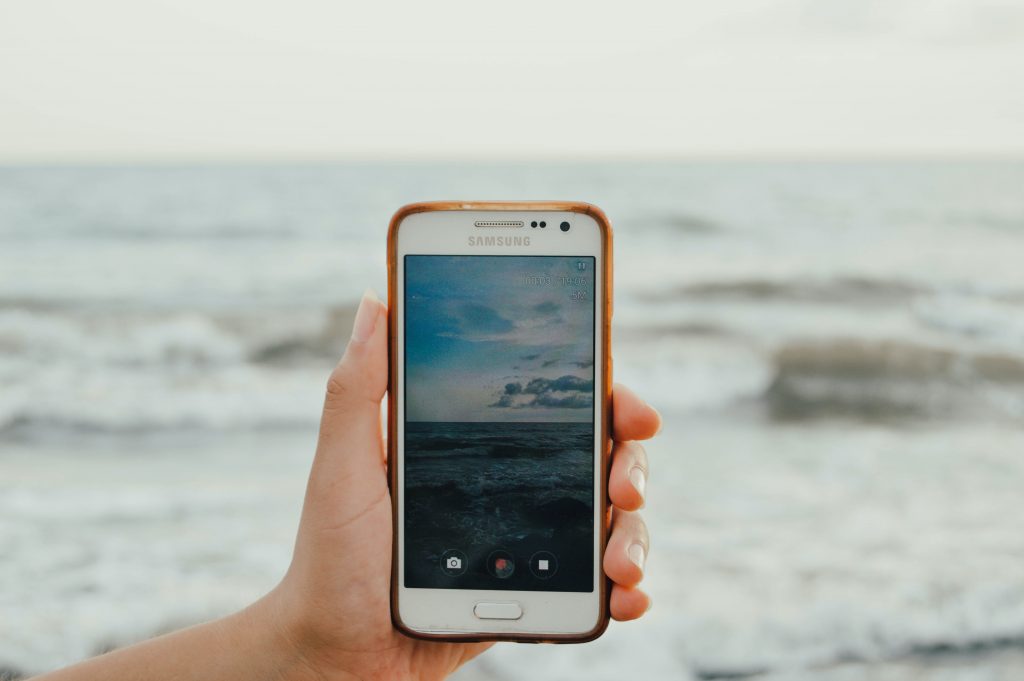 Mão com telemóvel num live streaming do mar
